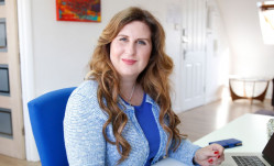 Smiling woman with long chestnut hair wearing blue